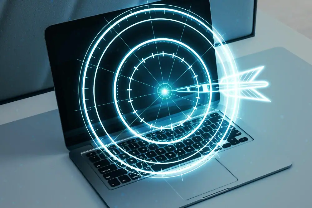 Hologramme de cible avec flèche au centre affiché devant un ordinateur portable, symbolisant objectif et stratégie digitale